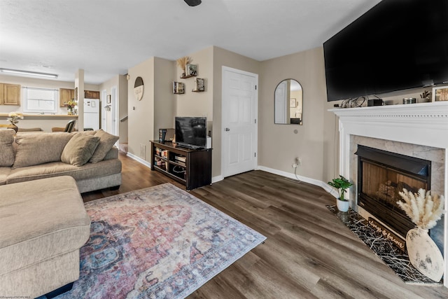 living area featuring baseboards, dark wood-style floors, and a fireplace