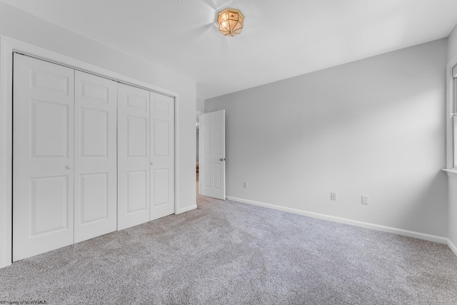 unfurnished bedroom featuring a closet, baseboards, and carpet flooring