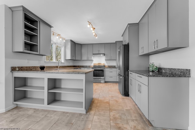 kitchen with gray cabinetry, appliances with stainless steel finishes, open shelves, and dark stone countertops
