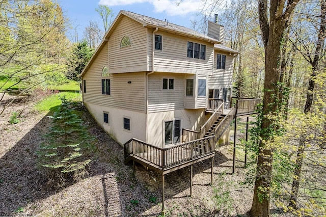 rear view of house featuring a deck, a chimney, and stairs