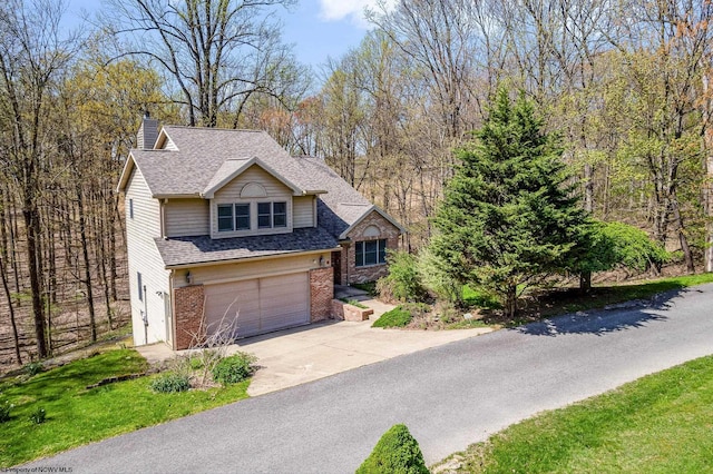 view of front of property with driveway, a chimney, roof with shingles, brick siding, and an attached garage