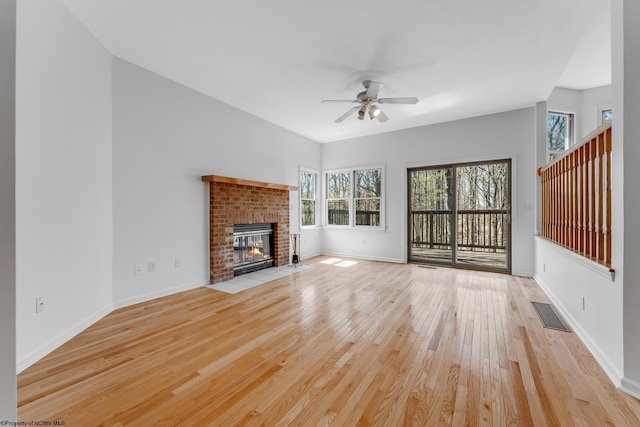 unfurnished living room featuring ceiling fan, visible vents, a fireplace, baseboards, and light wood-style floors
