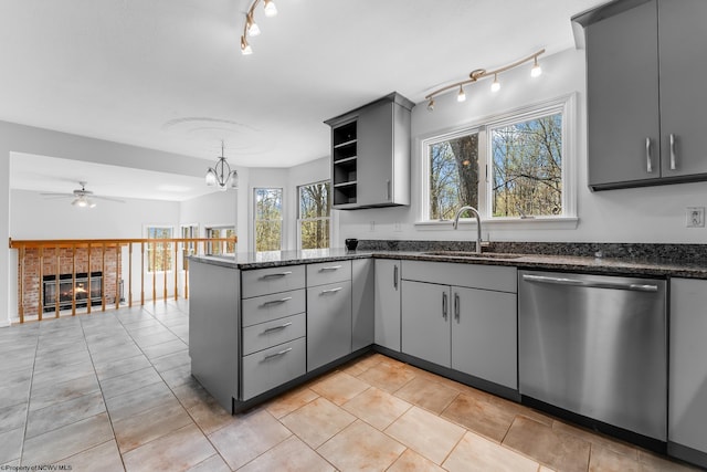 kitchen with open shelves, a peninsula, gray cabinets, a sink, and dishwasher