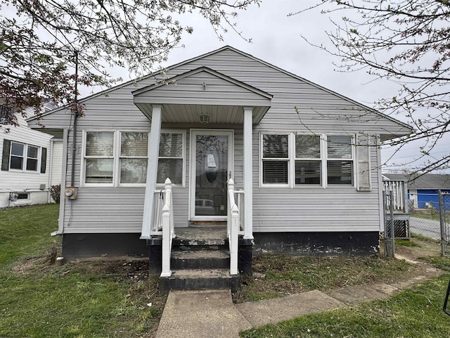 bungalow featuring a front lawn and fence