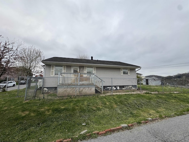 manufactured / mobile home with fence, a wooden deck, and a front yard