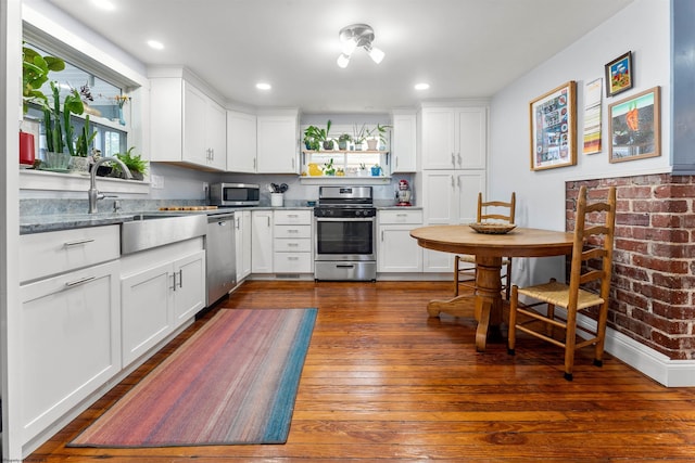 kitchen with a sink, white cabinets, stainless steel appliances, and dark wood-style floors