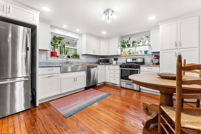 kitchen featuring open shelves, dark wood-style floors, white cabinetry, a sink, and stainless steel appliances