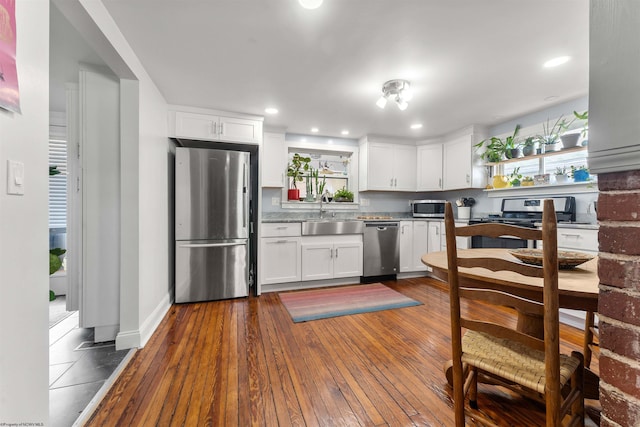 kitchen featuring dark wood-type flooring, a sink, white cabinets, and stainless steel appliances