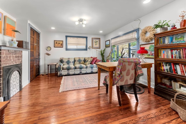 living room featuring a brick fireplace, recessed lighting, baseboards, and hardwood / wood-style floors