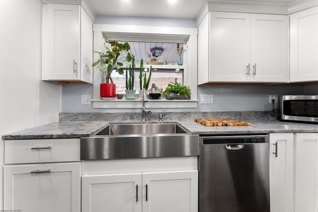 kitchen with a sink, light stone counters, stainless steel appliances, and white cabinetry