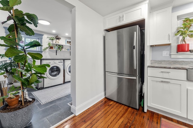 kitchen with light stone countertops, freestanding refrigerator, white cabinetry, baseboards, and washing machine and dryer