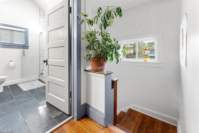 bathroom featuring baseboards, walk in shower, and toilet