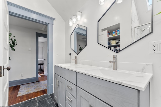 full bathroom with a sink, vaulted ceiling, double vanity, and wood finished floors