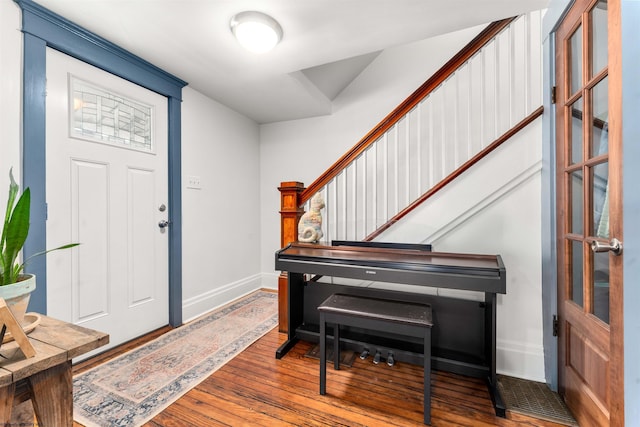 entrance foyer with baseboards, wood finished floors, and stairway