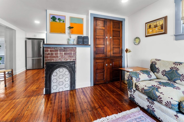 living room with recessed lighting, a brick fireplace, and dark wood-style flooring