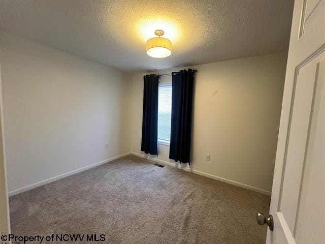 carpeted empty room featuring baseboards, a textured ceiling, and visible vents