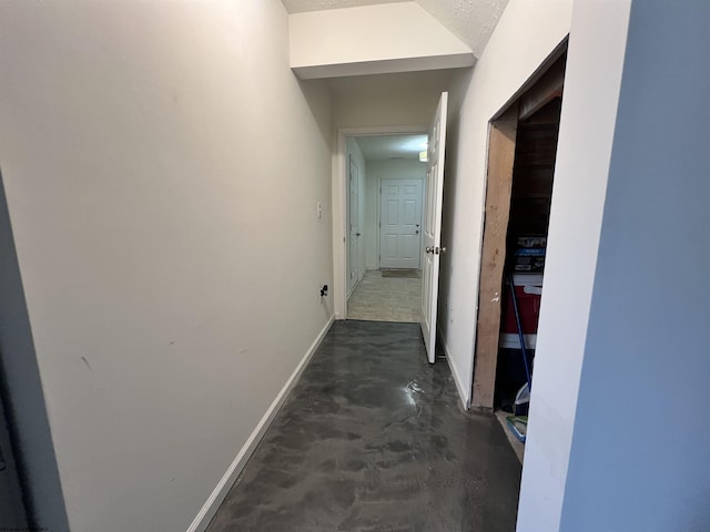 hall featuring baseboards and concrete floors