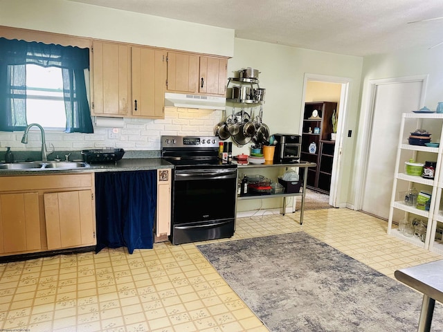 kitchen featuring dark countertops, a sink, black electric range oven, light floors, and under cabinet range hood
