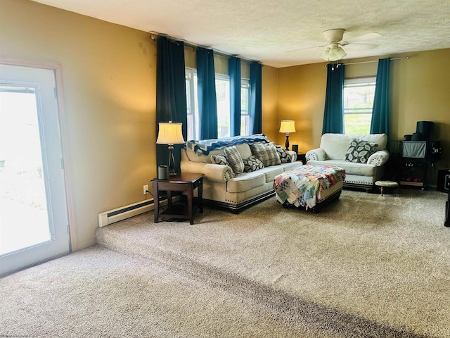carpeted living area with ceiling fan, a baseboard radiator, a textured ceiling, and a wealth of natural light
