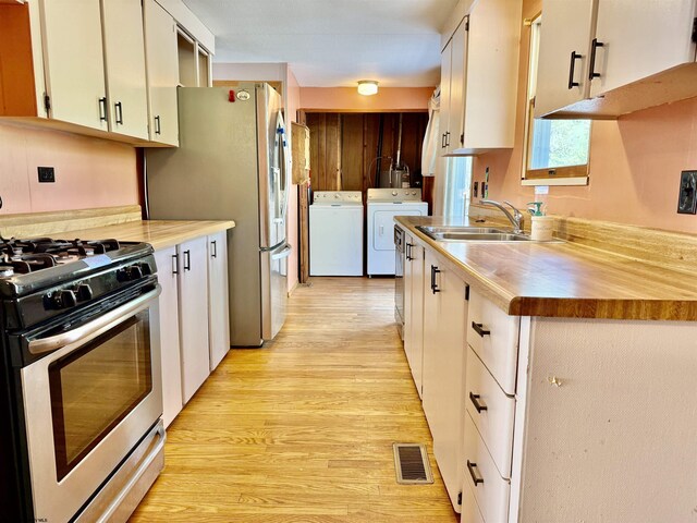 108 Toothman Run Rd, Rivesville, WV 26588 - kitchen featuring washing machine and clothes dryer, a sink, light wood-style flooring, stainless steel appliances, and visible vents