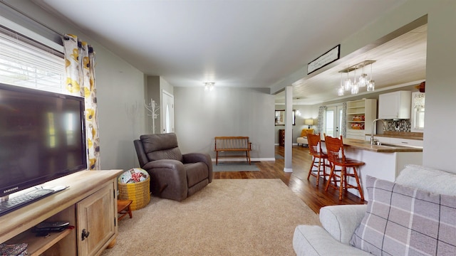 living area with baseboards, a notable chandelier, and wood finished floors
