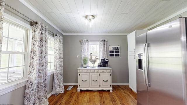 kitchen featuring stainless steel fridge, light wood-style flooring, a wealth of natural light, and white cabinets