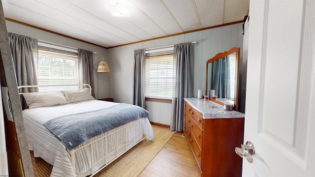 bedroom featuring ornamental molding, multiple windows, and light wood-style floors