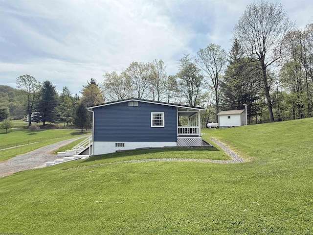 view of side of property featuring a lawn, an outbuilding, gravel driveway, and a shed