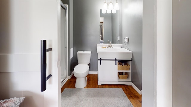 bathroom with a stall shower, wood finished floors, vanity, baseboards, and toilet