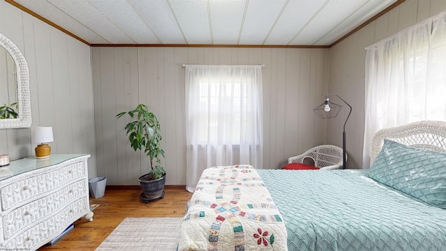 bedroom with crown molding, baseboards, and wood finished floors