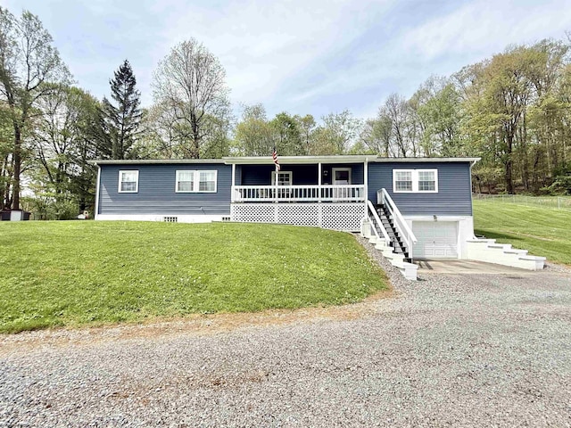 manufactured / mobile home featuring a garage, covered porch, a front yard, stairs, and driveway