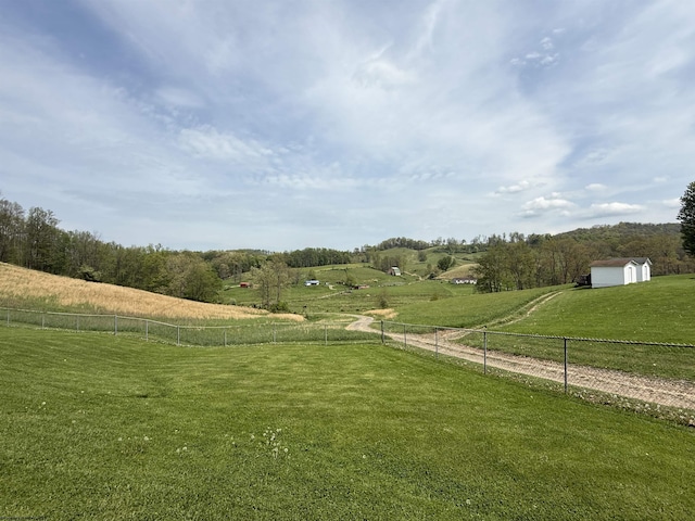 view of community with a yard, a rural view, fence, and a shed