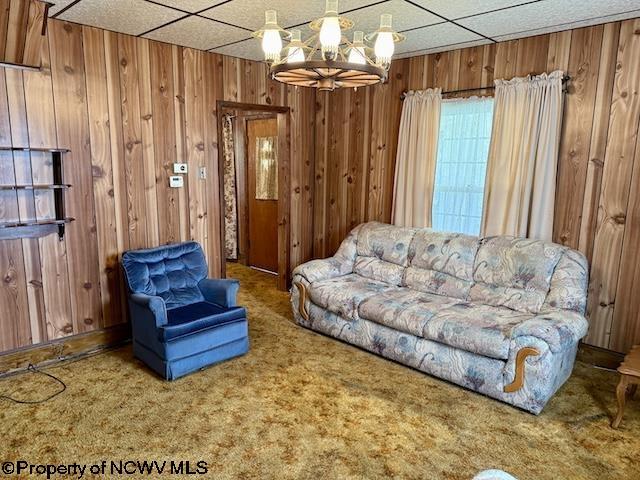 346 Parkway Ave, Anmoore, WV 26323 - living area featuring wood walls, a drop ceiling, a chandelier, and carpet flooring