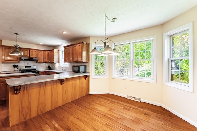 kitchen featuring visible vents, black microwave, stainless steel range with gas stovetop, a sink, and light wood-style flooring