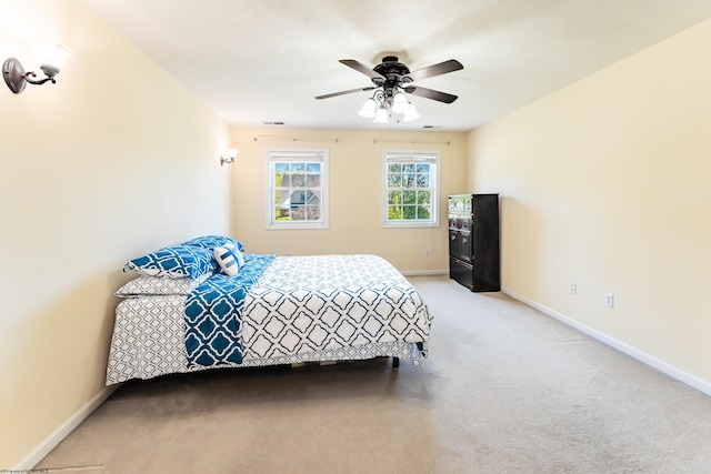 bedroom with baseboards, visible vents, a ceiling fan, and light colored carpet