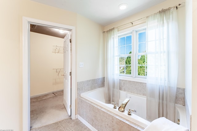 bathroom featuring tile patterned floors, a bath, and a spacious closet