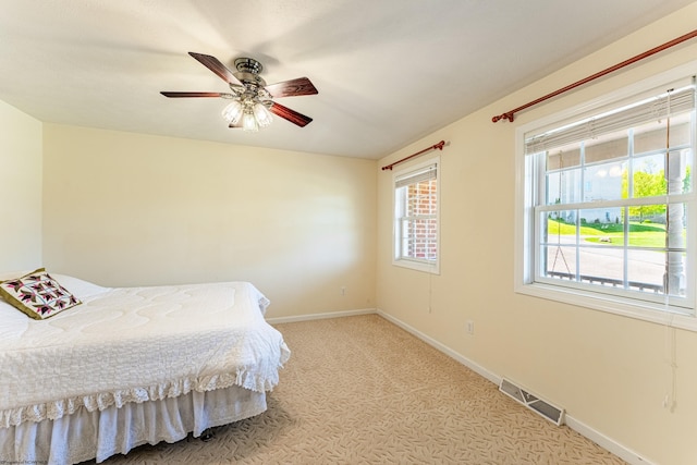 carpeted bedroom with a ceiling fan, baseboards, and visible vents