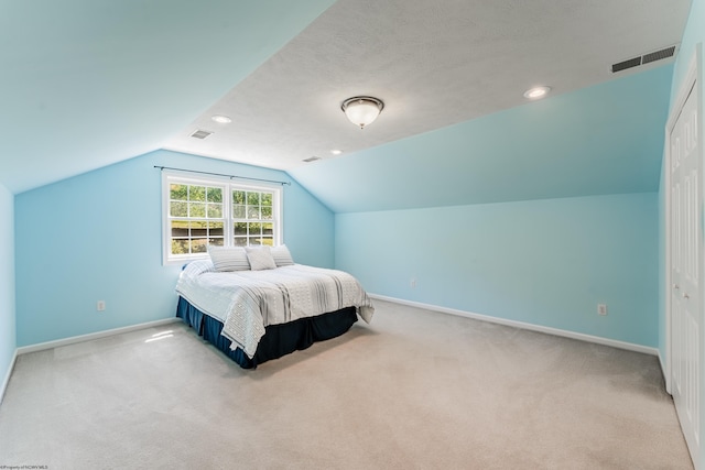 bedroom with carpet floors, baseboards, visible vents, and lofted ceiling