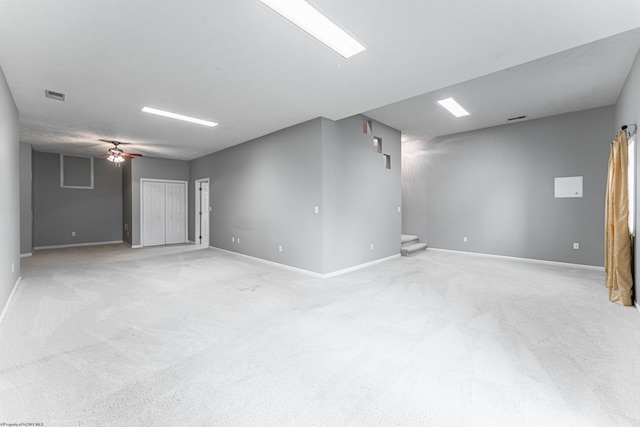 spare room with baseboards, ceiling fan, light carpet, and visible vents