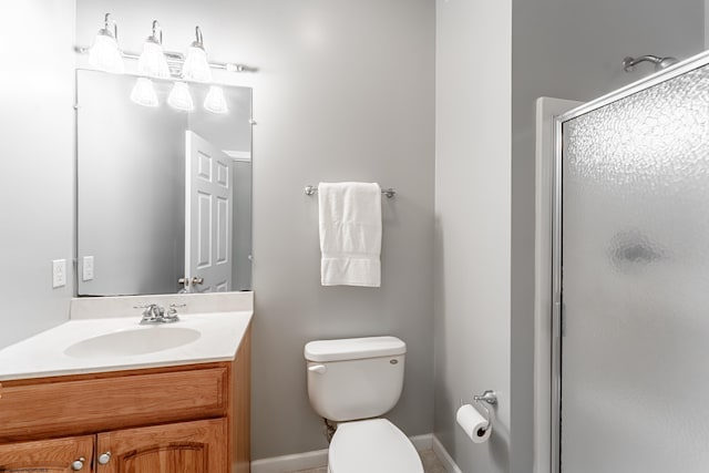 bathroom with vanity, baseboards, a stall shower, and toilet
