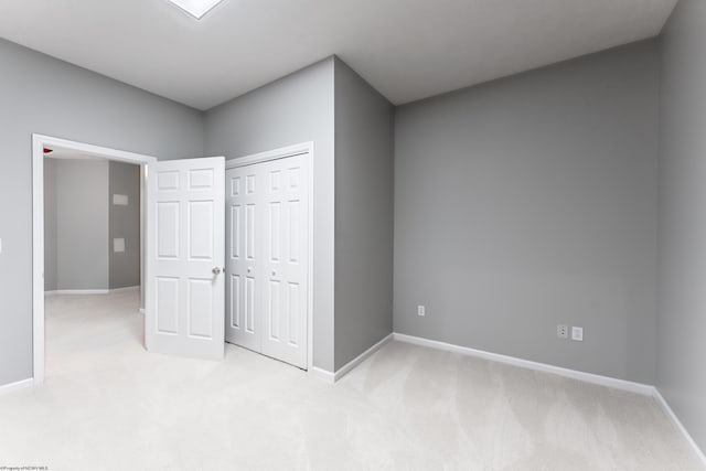 unfurnished bedroom featuring baseboards, a closet, and light carpet