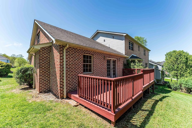 rear view of property with a lawn, a deck, brick siding, and roof with shingles