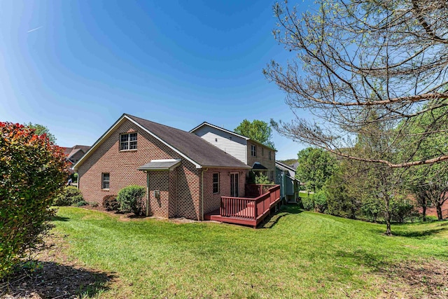 view of side of home with a lawn, roof with shingles, a deck, and brick siding