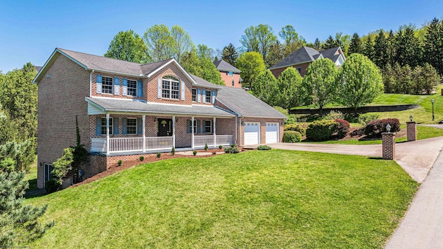 traditional-style house featuring a garage, a front yard, brick siding, concrete driveway, and a porch