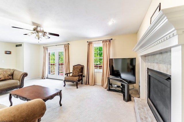 living area featuring a ceiling fan, visible vents, a fireplace, baseboards, and light carpet