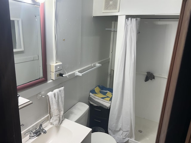 bathroom with a sink, a stall shower, and toilet
