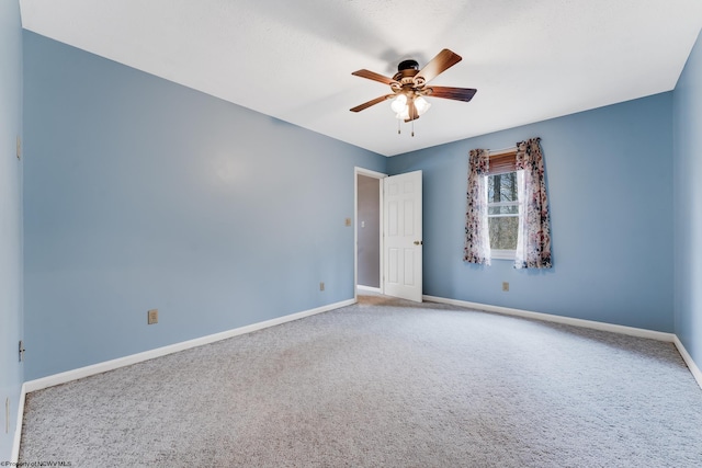 carpeted empty room featuring ceiling fan and baseboards