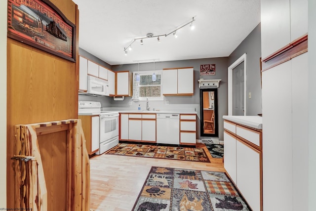 kitchen featuring a sink, light countertops, light wood-style floors, white appliances, and white cabinetry