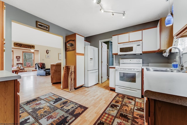 kitchen featuring white cabinets, a sink, white appliances, light countertops, and light wood-type flooring