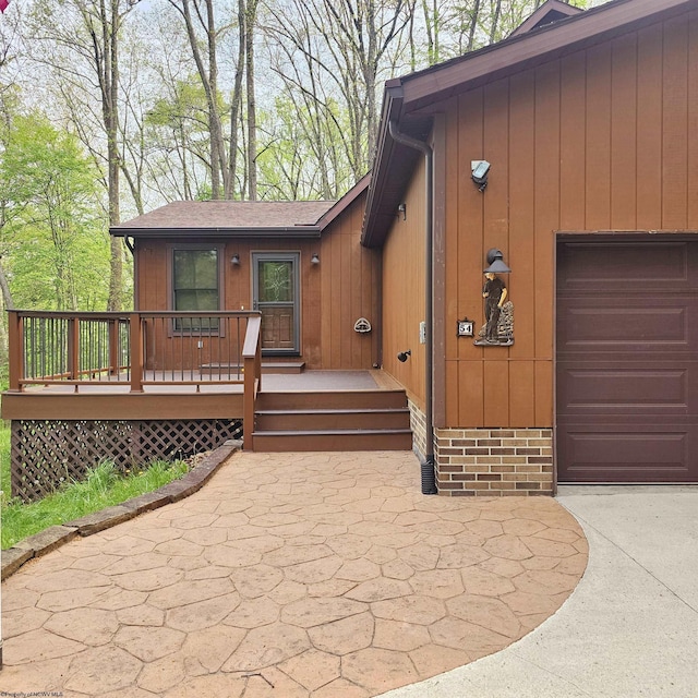 property entrance with a garage, a shingled roof, and concrete driveway